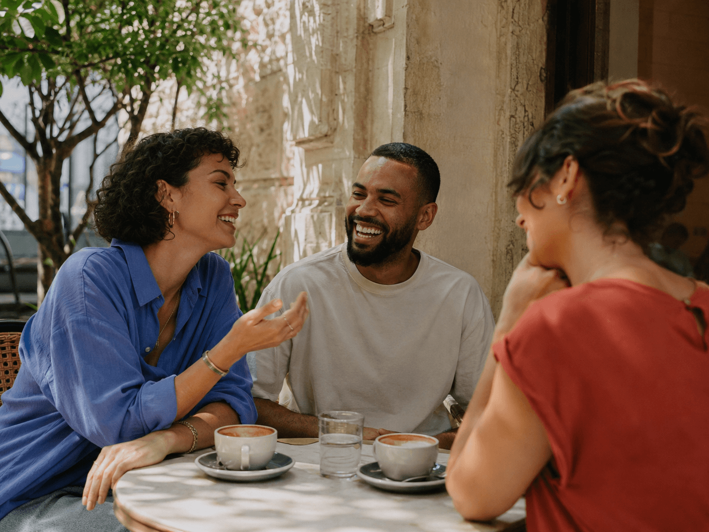 Illustrative campaign scene of three friends laughing over coffee